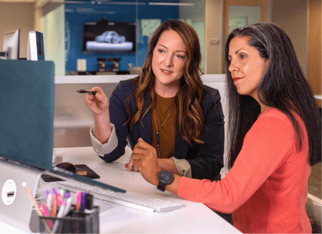 2 ladies sitting next to each other looking at something on a computer