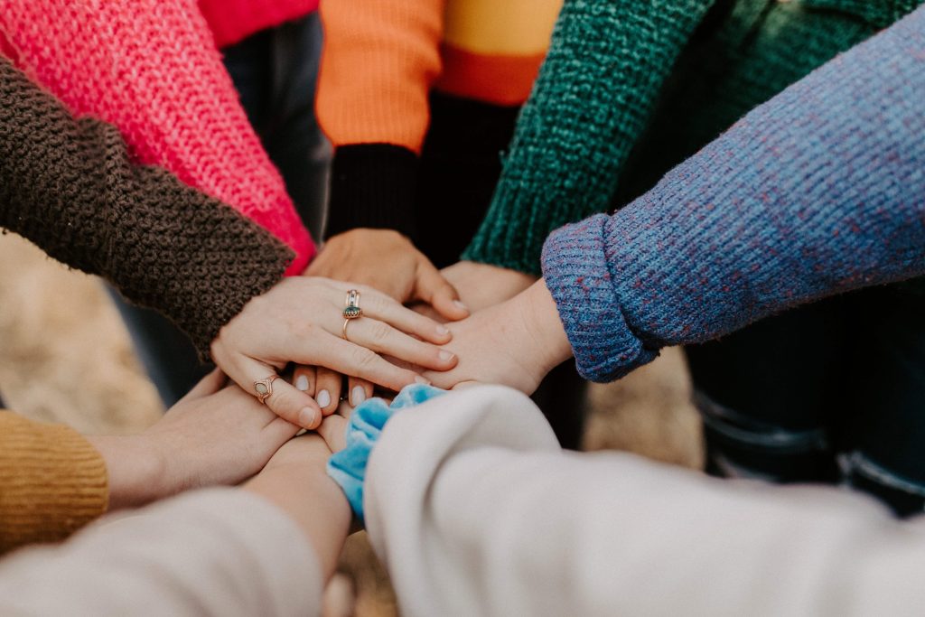 A group standing in a circle with their hands all stacked on top of each other in the middle